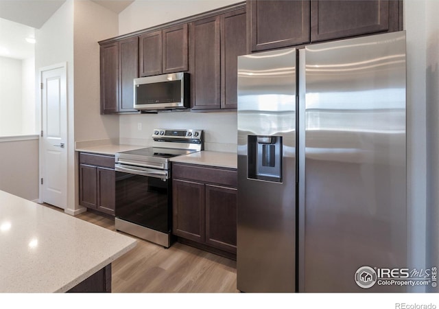 kitchen featuring dark brown cabinetry, light wood-type flooring, and appliances with stainless steel finishes