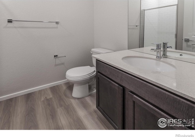 bathroom featuring hardwood / wood-style floors, vanity, a shower with shower door, and toilet