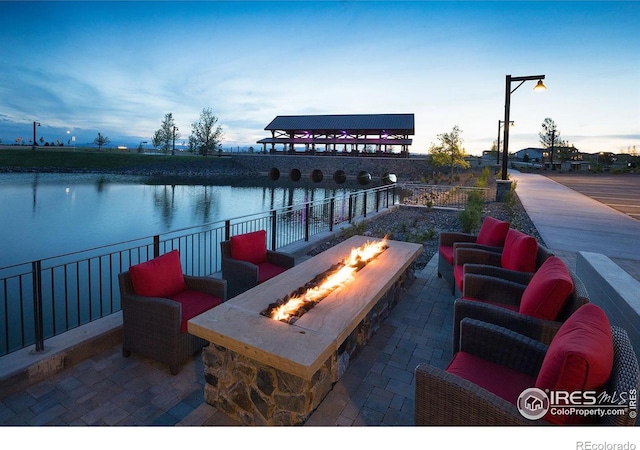 patio terrace at dusk featuring a water view and an outdoor fire pit