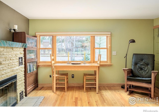 office with a stone fireplace and light hardwood / wood-style flooring