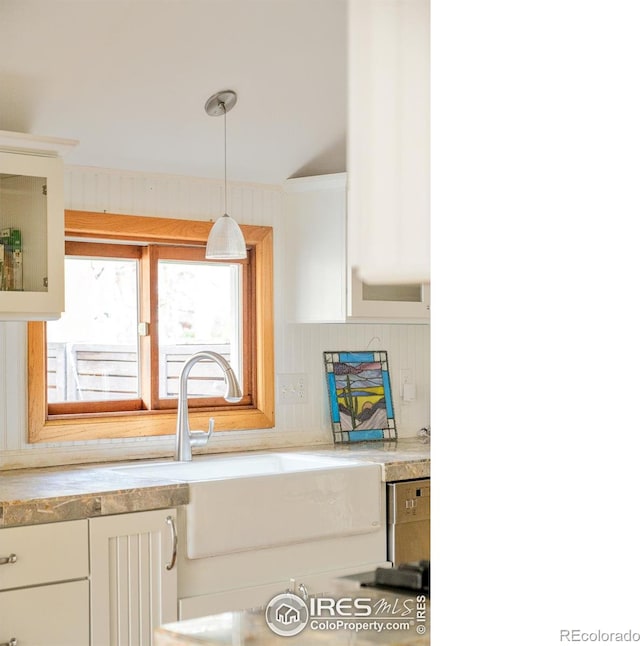 kitchen featuring hanging light fixtures, white cabinetry, sink, and decorative backsplash