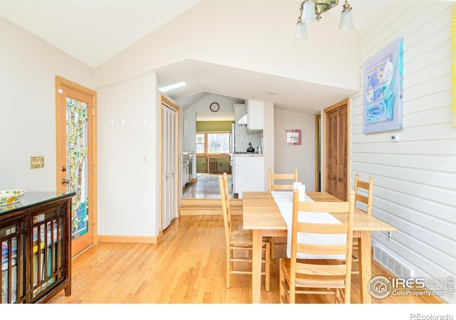 dining area with vaulted ceiling and light hardwood / wood-style flooring