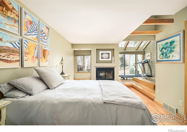 bedroom with vaulted ceiling with beams and wood-type flooring