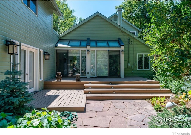 back of house with a wooden deck and a patio