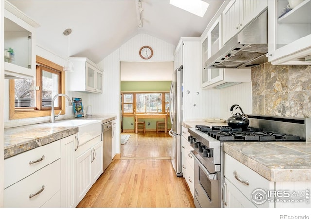 kitchen with lofted ceiling with skylight, hanging light fixtures, appliances with stainless steel finishes, range hood, and white cabinets