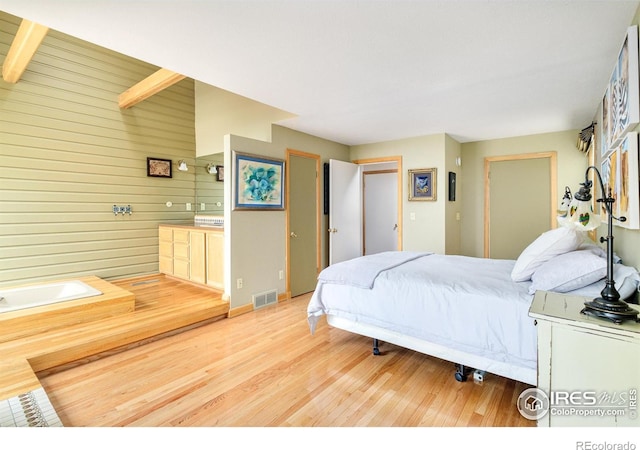 bedroom featuring wooden walls and light hardwood / wood-style flooring