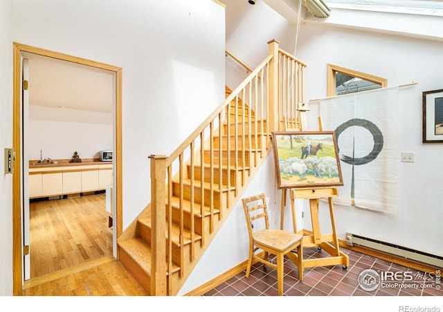 stairs featuring a baseboard radiator, sink, and hardwood / wood-style floors