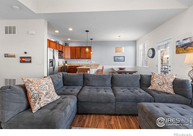 living area with recessed lighting, visible vents, and wood finished floors