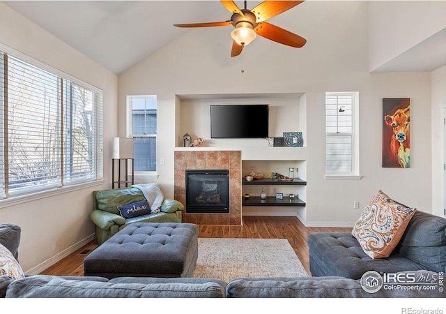 living area with lofted ceiling, baseboards, wood finished floors, and a tile fireplace