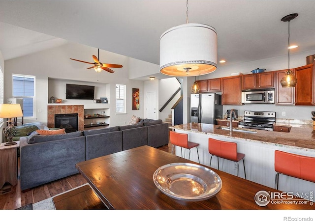 dining space with a ceiling fan, a tile fireplace, lofted ceiling, dark wood-style floors, and recessed lighting