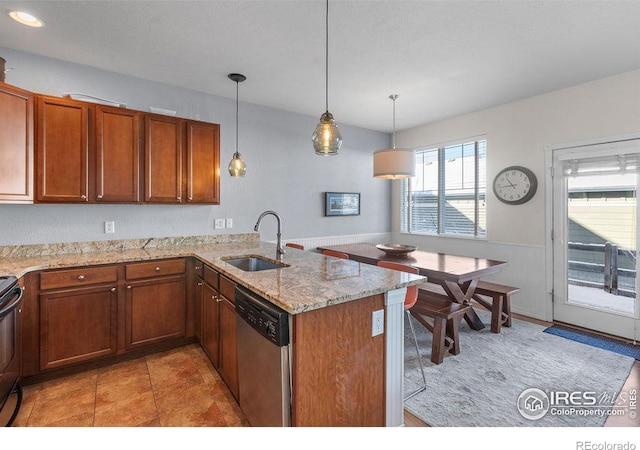 kitchen featuring light stone counters, decorative light fixtures, a sink, dishwasher, and a peninsula