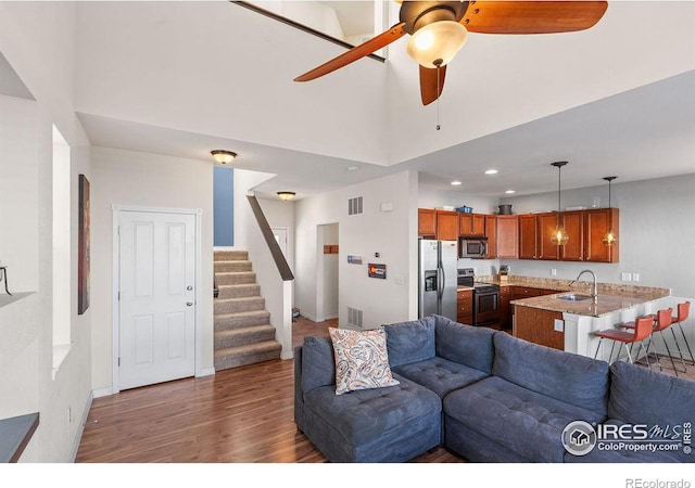 living room featuring baseboards, stairs, visible vents, and wood finished floors