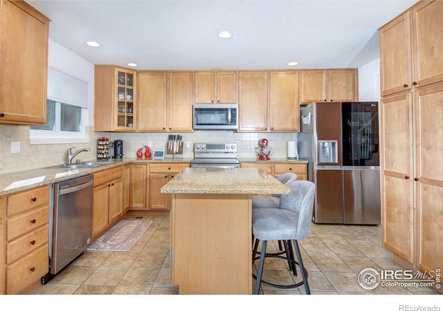 kitchen with a kitchen island, light brown cabinetry, sink, light stone counters, and stainless steel appliances