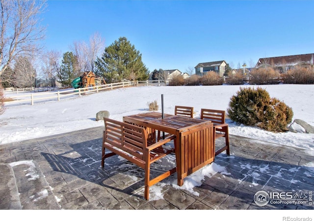 snow covered patio featuring a playground