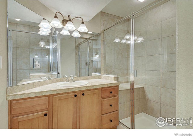 bathroom featuring a shower with door and vanity