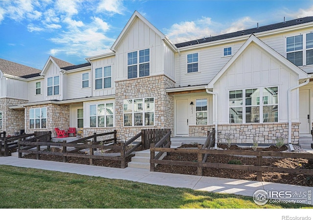 view of property featuring stone siding, a fenced front yard, and board and batten siding