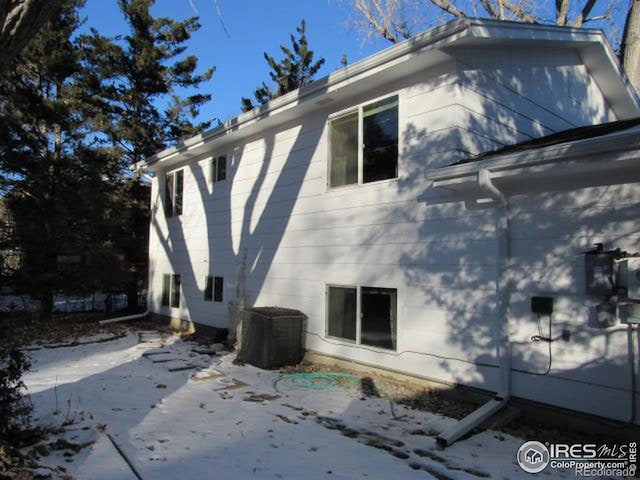 snow covered property with central AC and a patio