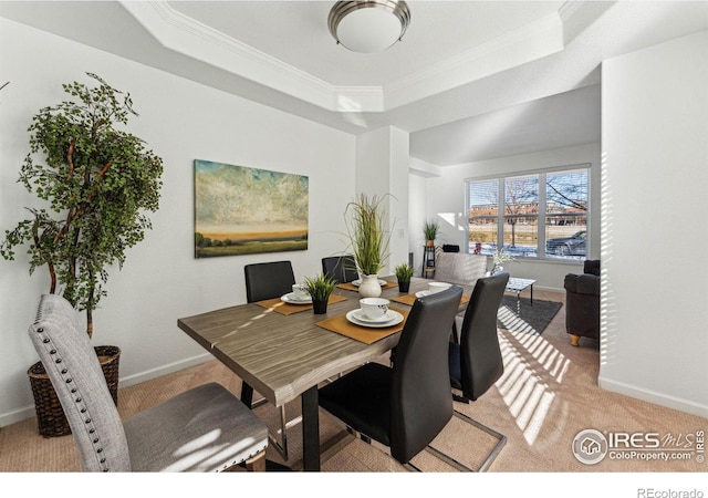 dining space featuring a raised ceiling, ornamental molding, and light carpet