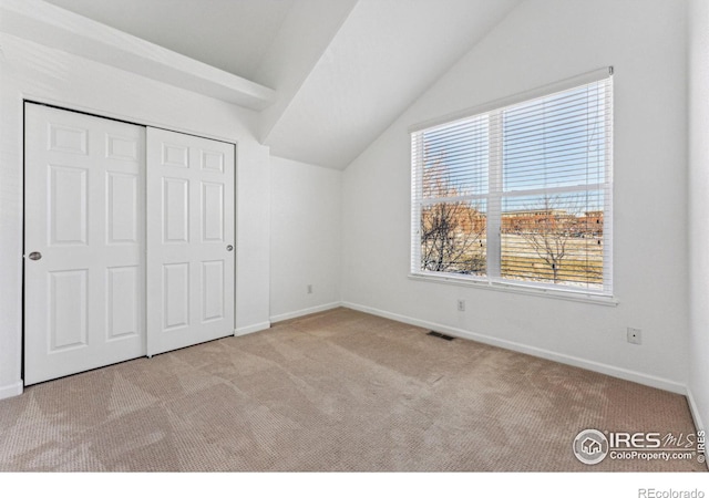 unfurnished bedroom with a closet, light carpet, and vaulted ceiling