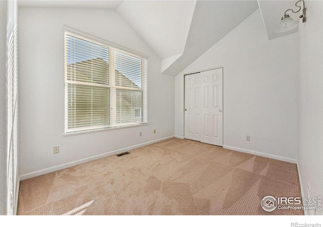 unfurnished bedroom with light carpet and vaulted ceiling