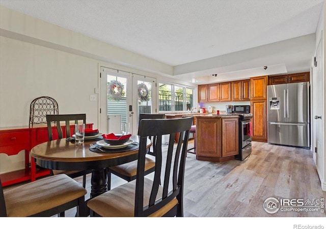 kitchen with a center island, french doors, light hardwood / wood-style flooring, a textured ceiling, and appliances with stainless steel finishes