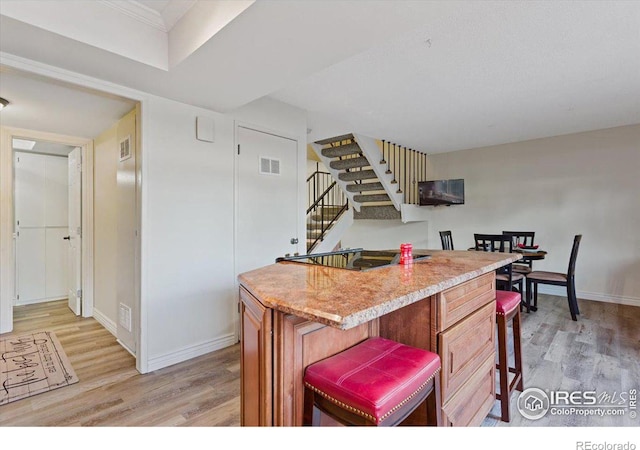 kitchen with a kitchen bar, light hardwood / wood-style flooring, a kitchen island, and electric cooktop