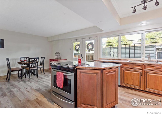 kitchen featuring stainless steel electric range oven, sink, a kitchen island, and light hardwood / wood-style flooring