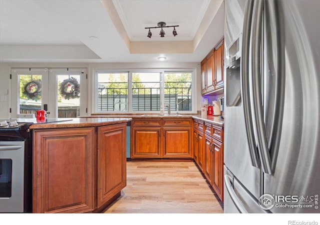 kitchen with french doors, a raised ceiling, light hardwood / wood-style flooring, stainless steel refrigerator with ice dispenser, and ornamental molding