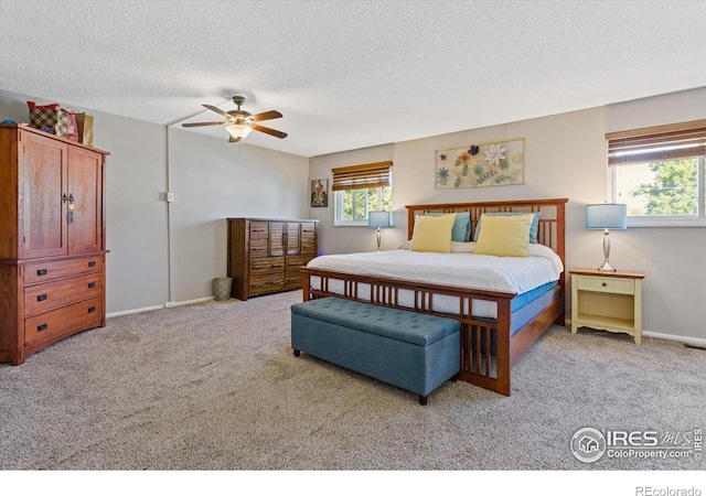 carpeted bedroom with ceiling fan and a textured ceiling