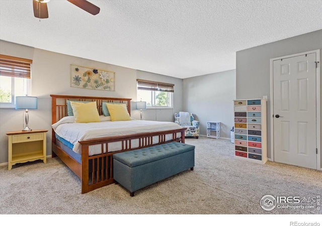 carpeted bedroom featuring ceiling fan and a textured ceiling