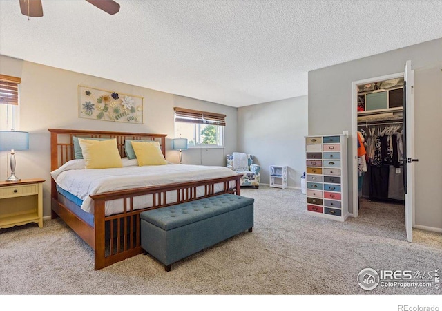 bedroom with ceiling fan, light colored carpet, a textured ceiling, and a closet