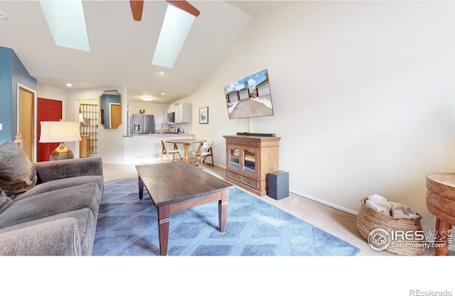 carpeted living room with vaulted ceiling with skylight