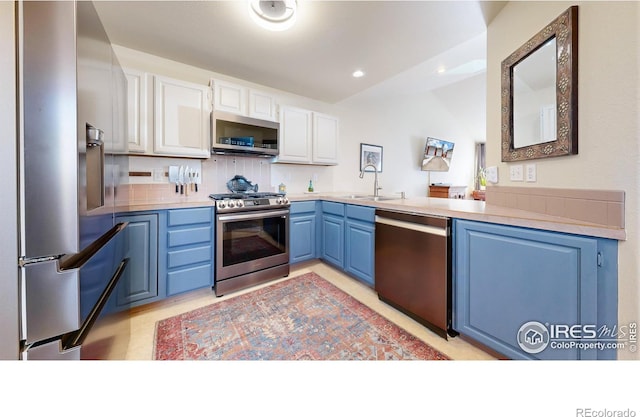 kitchen featuring backsplash, white cabinets, blue cabinets, sink, and stainless steel appliances