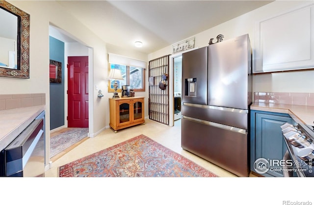 kitchen featuring stainless steel fridge and white cabinets