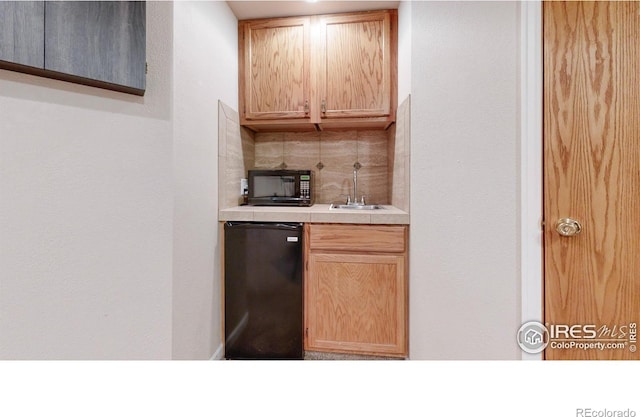 kitchen with light brown cabinets, backsplash, fridge, and sink