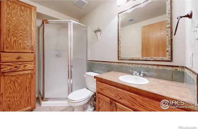 bathroom with vanity, tile patterned flooring, toilet, walk in shower, and tile walls