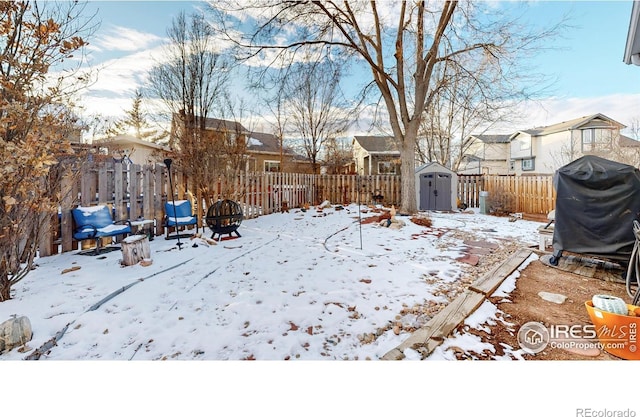 yard covered in snow with a shed and an outdoor fire pit