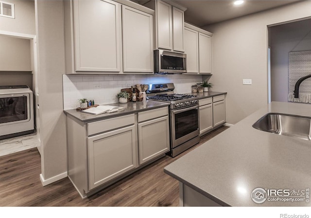 kitchen featuring dark wood-type flooring, sink, washer / dryer, and stainless steel appliances