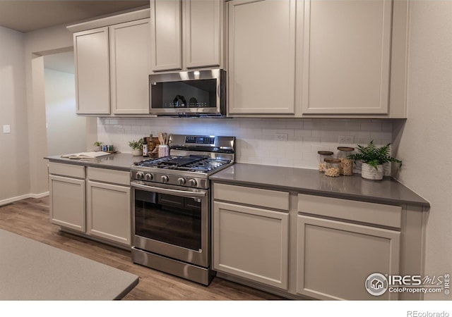 kitchen featuring backsplash, appliances with stainless steel finishes, white cabinetry, and light hardwood / wood-style floors