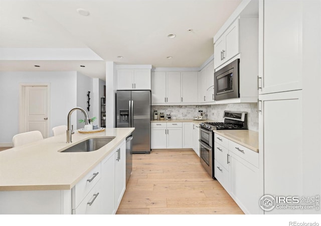 kitchen with a center island with sink, white cabinetry, and appliances with stainless steel finishes