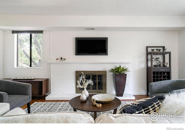 living room with a fireplace, wood-type flooring, and a textured ceiling