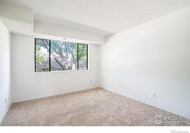 carpeted empty room featuring a textured ceiling