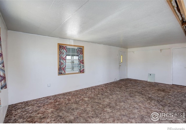 carpeted empty room featuring a textured ceiling