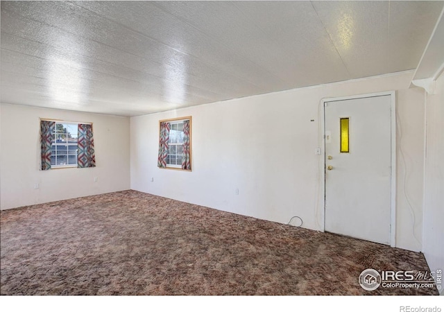 carpeted empty room with a textured ceiling