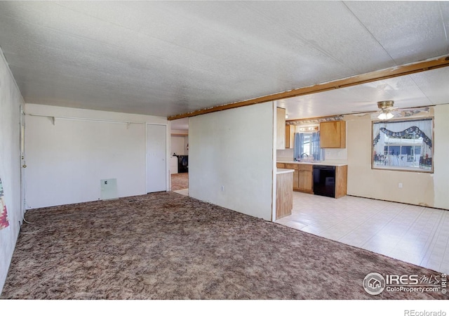 unfurnished living room featuring light carpet, sink, ceiling fan, and a textured ceiling