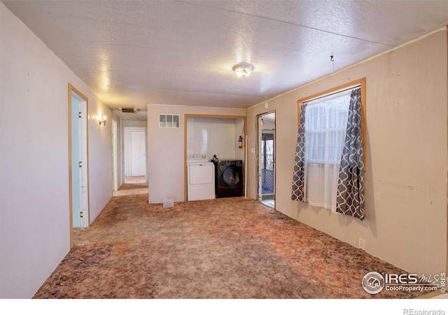 unfurnished living room featuring carpet flooring, a textured ceiling, and washer and clothes dryer