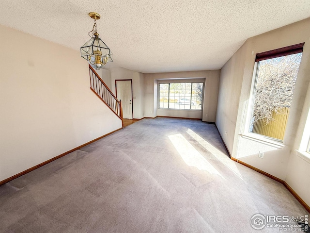 unfurnished living room with carpet, a chandelier, and a textured ceiling