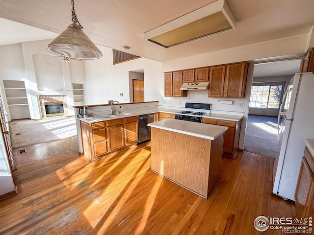 kitchen featuring stainless steel dishwasher, range with gas cooktop, white refrigerator, decorative light fixtures, and a center island