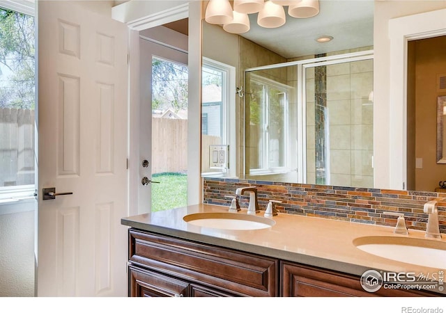 bathroom featuring vanity, a shower with door, and backsplash