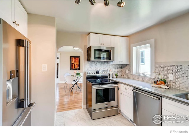 kitchen featuring appliances with stainless steel finishes, decorative backsplash, and white cabinets